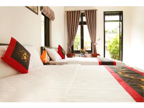 two white beds in a room with a window at Sunny Garden Homestay in Hoi An