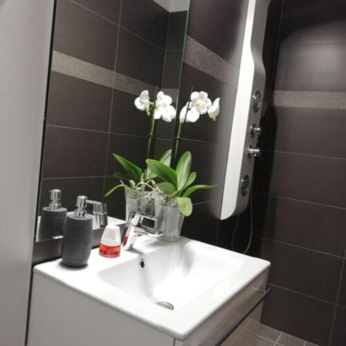 a bathroom sink with a vase of flowers on it at Téged Vártunk Vendégház in Bakonyoszlop