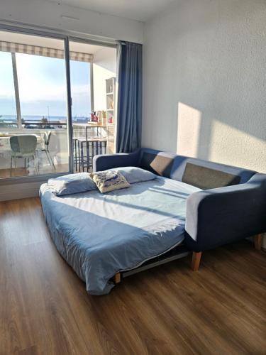 a bedroom with a blue bed with a balcony at Superbe vue sur mer à Sète in Sète