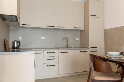 eine Küche mit weißen Schränken und einem Tisch in der Unterkunft Planet Gemini Residence in Niš