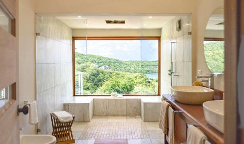 a bathroom with two sinks and a tub and a large window at The Inn at English Harbour in English Harbour Town