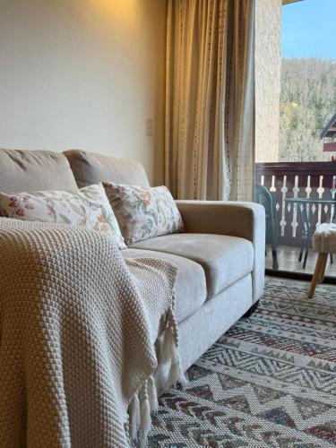 a living room with a couch and a window at Nevados de chillan , edificio los coigues in Nevados de Chillan