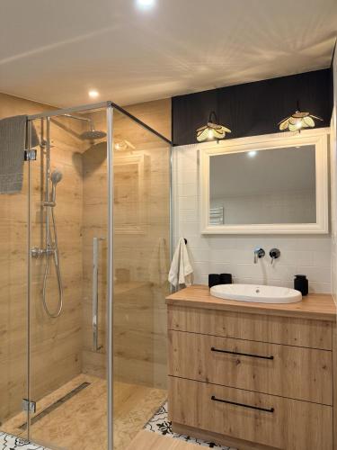 a bathroom with a glass shower and a sink at Apartamenty Guzik 31 in Krosno