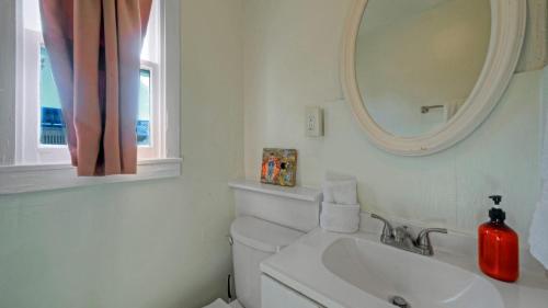 ein weißes Badezimmer mit Waschbecken und Spiegel in der Unterkunft Walk to Alister St Near Dining King Suite w Private Yard Fire Pit Casa Santori by AvantStay in Port Aransas