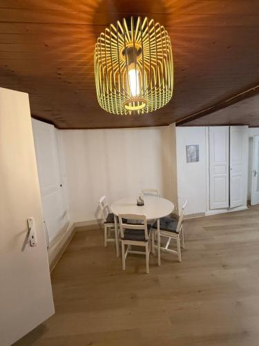 een eetkamer met een tafel, stoelen en een kroonluchter bij Face au chateau in Vizille
