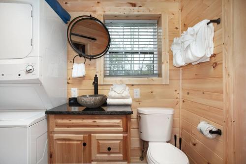 un bagno con un water, un lavandino e uno specchio di Whiskey Duo 2 Cabins SidebySide HotTubs Firepit a Walnut Grove