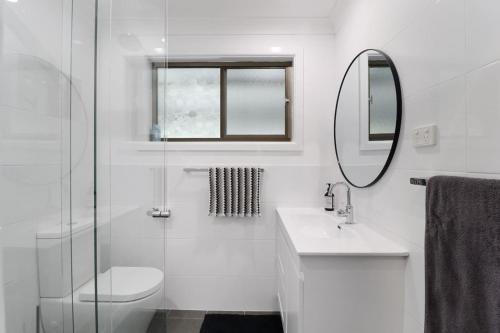 a bathroom with a toilet and a sink and a mirror at Lakeside Getaway Halekulani in Budgewoi