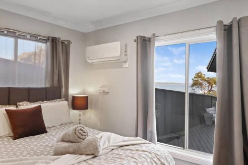 a bedroom with a bed and a large window at Bayview Bliss Brightwaters in Morisset East