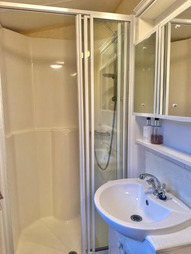 a white bathroom with a shower and a sink at East Coast in Port Seton