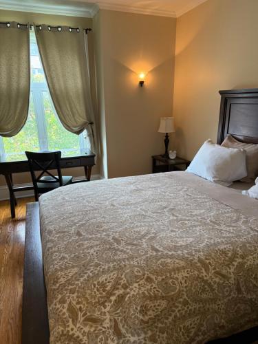 Un dormitorio con una cama y un escritorio y una ventana. en The Century House Bed and Breakfast Ottawa, en Ottawa