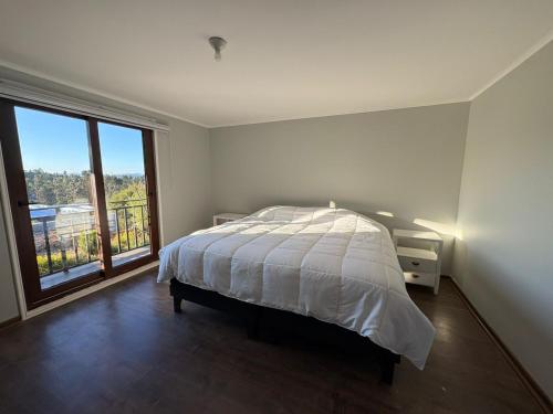 a white bedroom with a bed and a large window at Casa El Quillay in Los Quillayes