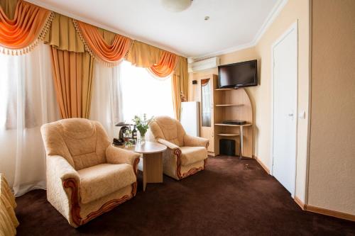 a hotel room with two chairs and a table and a television at Bukovyna Hotel in Chernivtsi