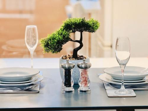 a table with two wine glasses and a bonsai tree at Cosy 1 bed flat, sleeps 4, free parking in Bradford