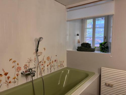 a bathroom with a green tub and a window at Dammablick Göschenen in Göschenen