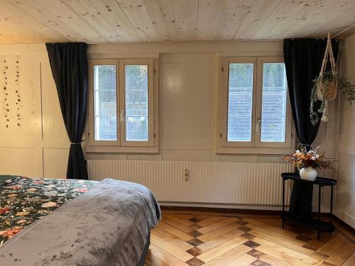 a bedroom with a bed and windows and a wooden floor at Dammablick Göschenen in Göschenen