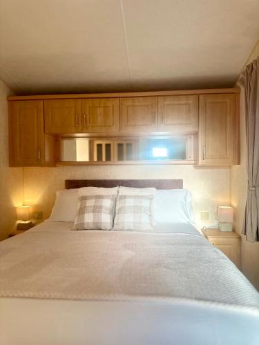 a bedroom with a white bed with wooden cabinets at East Coast in Port Seton