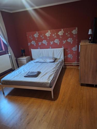 een slaapkamer met een bed in een kamer met houten vloeren bij Kisház in Kisvárda