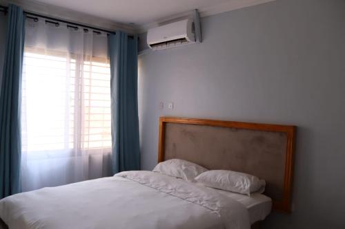 a bedroom with a white bed with a window at Tical Apartments in Lilongwe