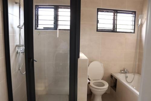 a bathroom with a shower and a toilet and a sink at Tical Apartments in Lilongwe