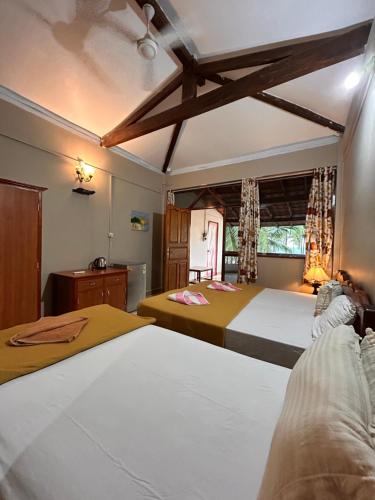 a bedroom with two beds and a window at Maria Paulo Guest House Bar and Restaurant in Agonda