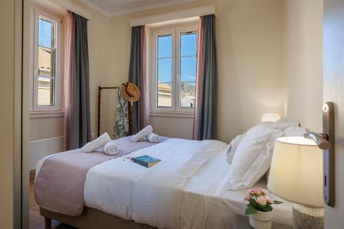 - une chambre avec un grand lit blanc et 2 fenêtres dans l'établissement The Lucky 12, à Corfu