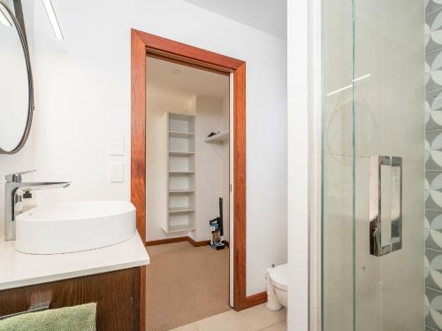 a bathroom with a sink and a toilet and a mirror at Summer Palms - Tairua Holiday Home in Tairua