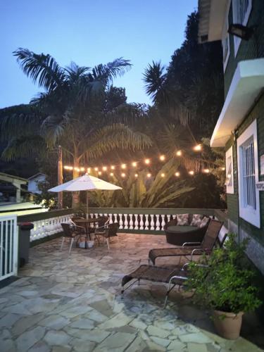un patio con una mesa y una sombrilla por la noche en Chales Virena, en Ubatuba