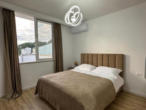 ドゥラスにあるAmea Apartmentsの大きなベッドと大きな窓のある寝室