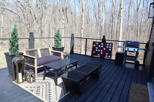 a deck with benches and a grill and trees at Secluded A-Frame Hocking Hills Hot Tub Fire Pit in South Bloomingville