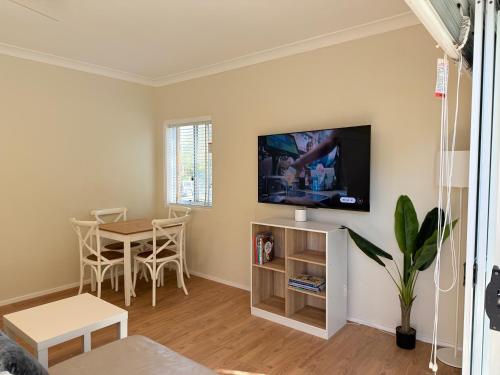 a living room with a table and a tv on a wall at 2 Bedroom Apartment - Heart of Cronulla in Cronulla