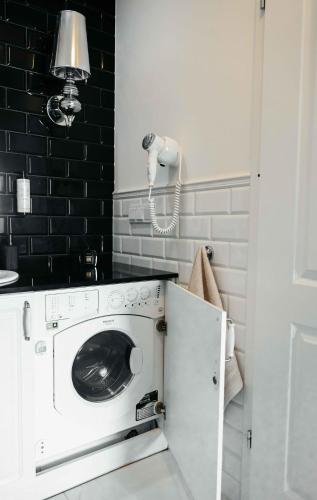 a washer and dryer in a bathroom with black tiles at Lumina OVO in Wrocław