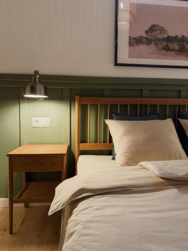 a bed with a wooden headboard next to a table at Apartamenty Guzik 32 in Krosno
