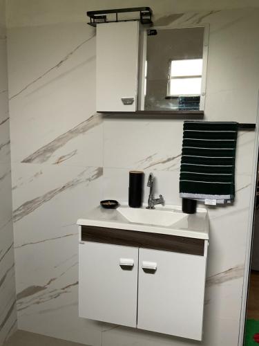 a white bathroom with a sink and a mirror at Casa de campo in Extrema