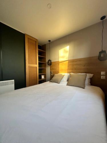 a bedroom with a large white bed with two pillows at Camping Papillon Kinrooi - Vakantiehuis Familie 6P in Kinrooi