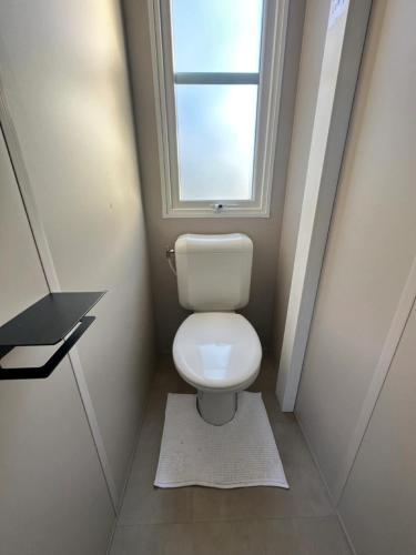 a small bathroom with a toilet with a window at Camping Papillon Kinrooi - Vakantiehuis Familie 6P in Kinrooi