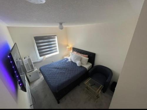 a small bedroom with a blue bed and a chair at Budget Friendly Home in Oshawa