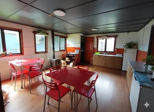 a kitchen and dining room with red tables and chairs at Mate Sur Hostal in Cochrane