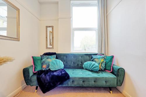 a green couch in a living room with pillows at Spacious Home by the Sea - Families, Contractors, Parking, WiFi, Sleeps 6, Long Stays - CLARK PROPERTY ESTATES in Southend-on-Sea