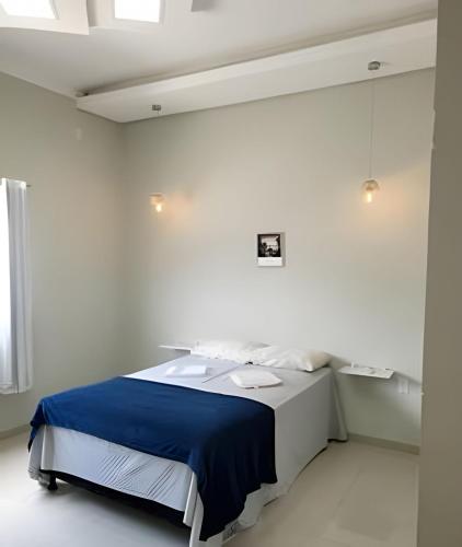 a white room with a bed with a blue blanket at Casa ampla e confortável in Corumbá