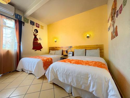 a hotel room with two beds with orange and white sheets at Hotel Escalada in Oaxaca City