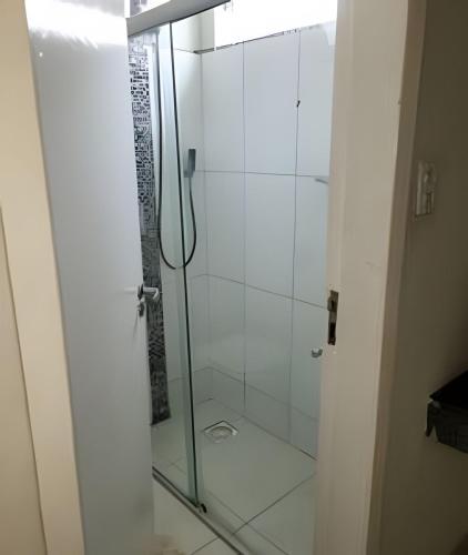 a shower with a glass door in a bathroom at Casa ampla e confortável in Corumbá