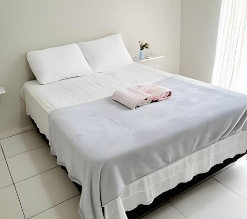 a white bed with white sheets and pink towels on it at Sobrado 6 amplo e confortável em condomínio in Corumbá