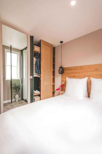 a bedroom with a white bed and a mirror at Camping Papillon Kinrooi - Vakantiehuis Premium 4P in Kinrooi