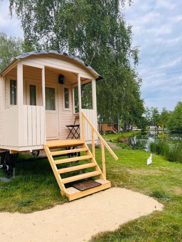 a gazebo with a porch and stairs next to a river at Camping Papillon Kinrooi - Pipowagen 2p terras in Kinrooi