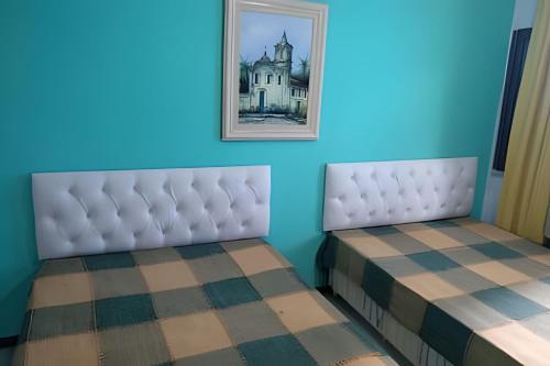 two beds in a room with a picture on the wall at Itaparica - Praia de Ponta de Areia in Itaparica Town