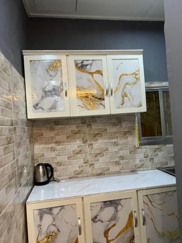een keuken met witte kasten met gouden verf op de muur bij Tataicha Stydio 1 in Ndjamena