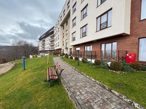 a building with two benches in the grass next to a building at Amprtman PETKOVIĆ NLux 110 Milmari resort in Kopaonik