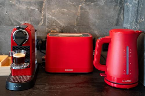 two red toasters and a coffee maker on a counter at The Saints Inn in Athens