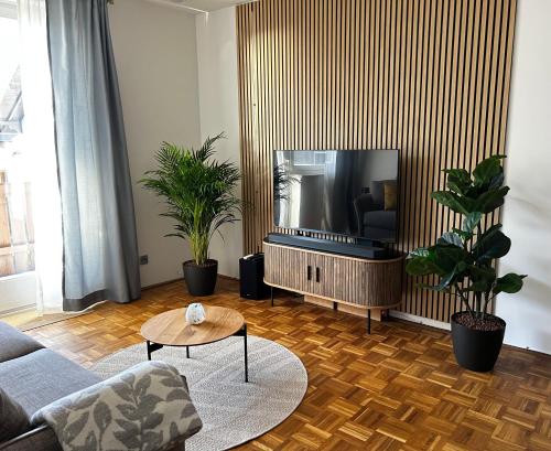 a living room with a tv and some plants at Wallersee Retreat in Neumarkt am Wallersee