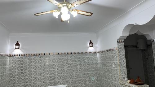 a bathroom with a ceiling fan and a tiled wall at Villa Haryouli in Azemmour